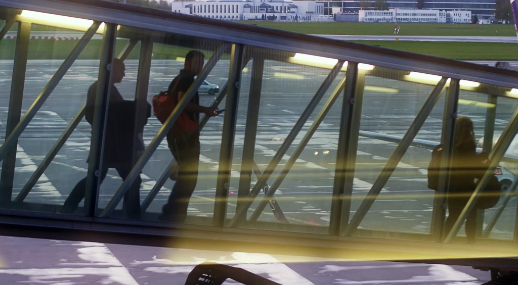 videoblocks-warsaw-poland-april-14-2017-passengers-walking-in-a-glass-jet-bridge-boarding-a-plane-at-the-airport-in-the-evening-4k-video_bcxv93xkce_thumbnail-full01